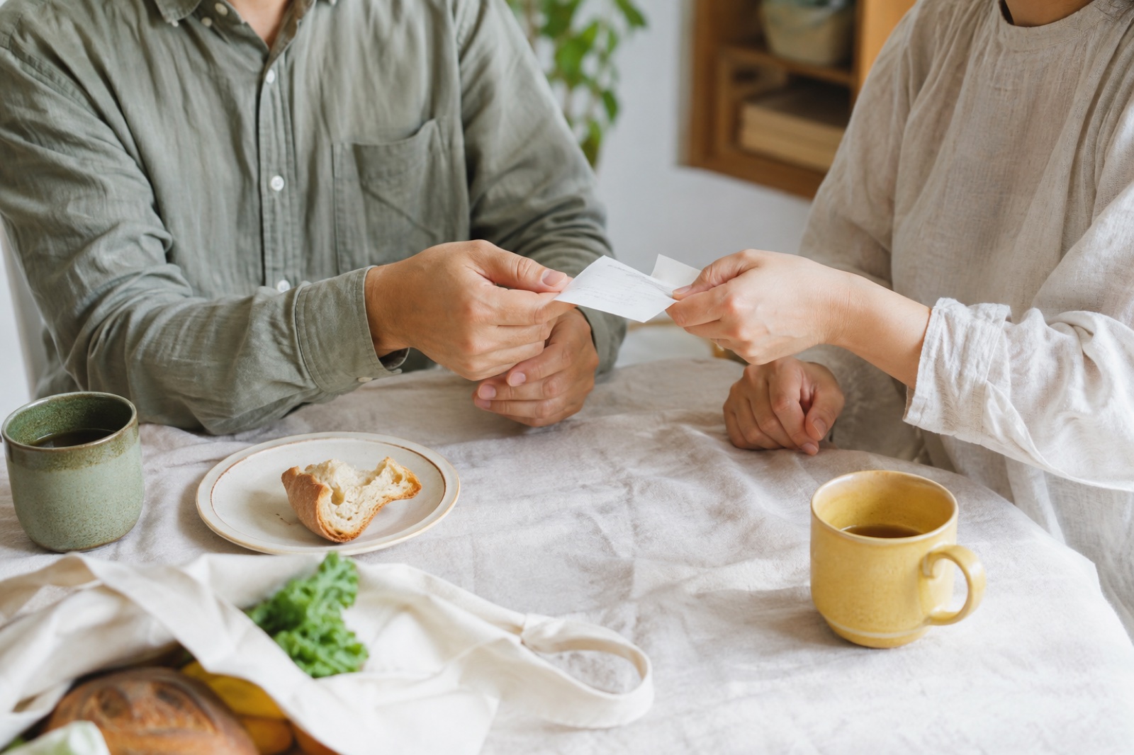 朝の食卓で、ふたりが買い物のレシートを確認しているイメージ